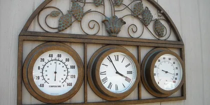 Alte Uhr mit Thermometer an der Wand