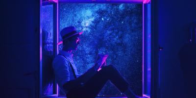 Mann sitzt nachts am offenen Fenster